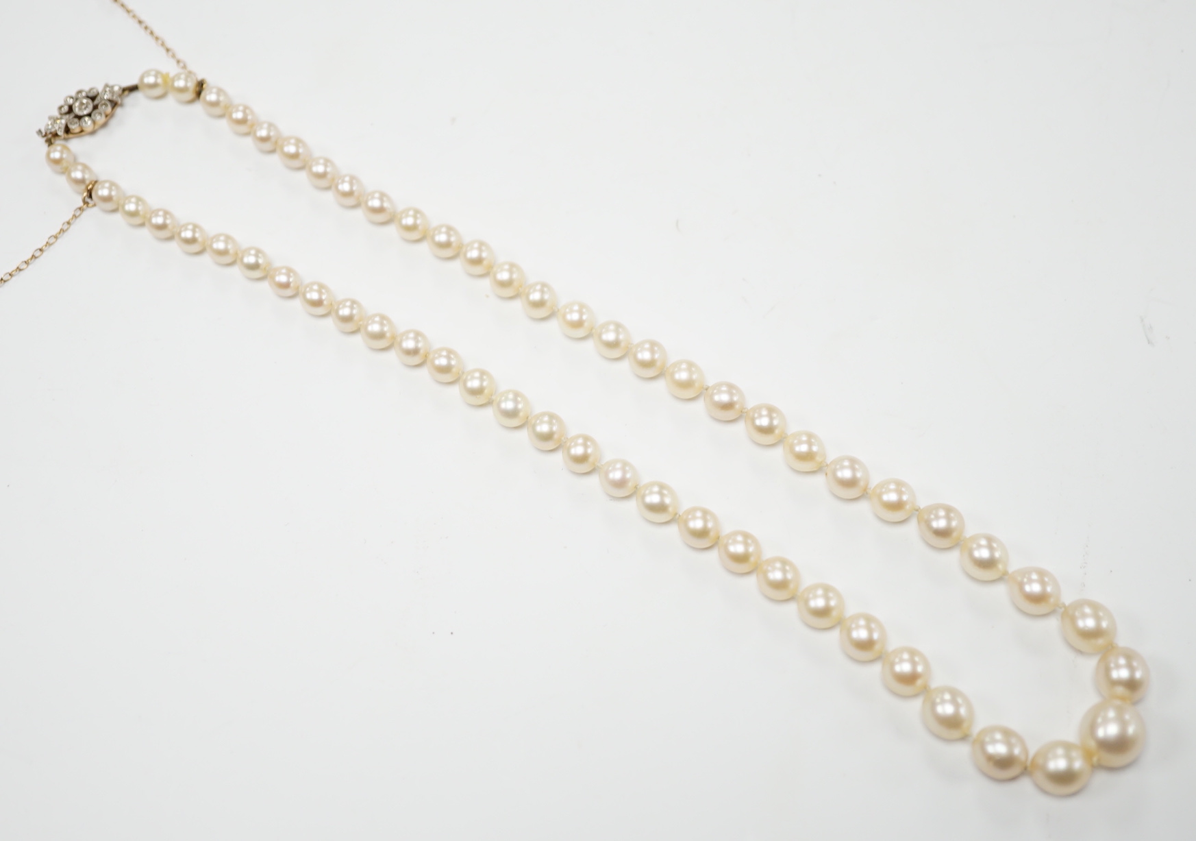 A single strand graduated cultured pearl necklace with millegrain set diamond cluster and yellow metal clasp, 40cm.